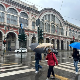 persone sotto la pioggia davanti a Porta Nuova